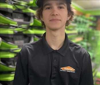 Employee in Black SERVPRO shirt against a green background