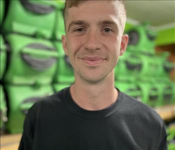 Employee in black servpro polo against a green background