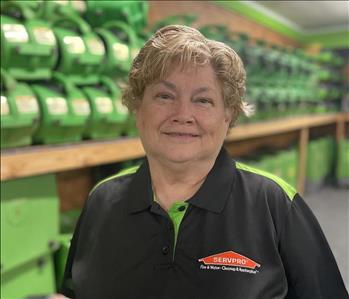 Female employee smiling in a black servpro shirt in front of a green background