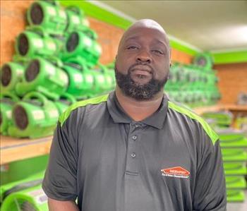 Servpro employee in black polo in front of a green background
