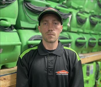employee in a black polo against a green background