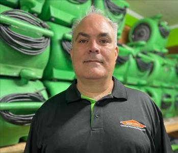 SERVPRO Employee with a black polo in front of a green background