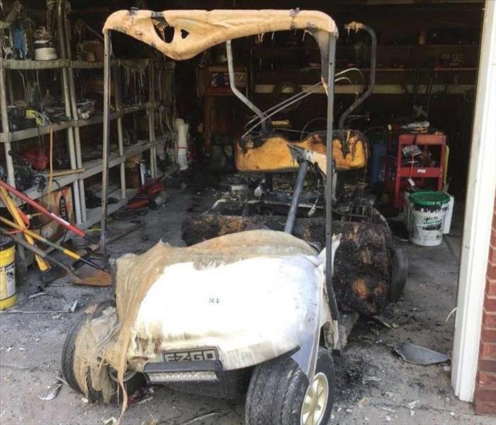 Golf cart in garage with fire damage. behind is more fire damage caused by golf cart charging