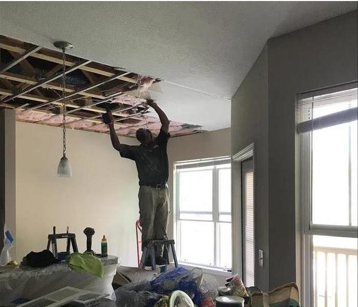 SERVPRO Technician on a ladder in the kitchen repairing the water damaged ceiling
