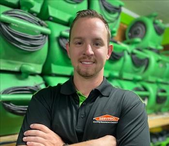 SERVPRO employee in a black polo in front of a green background
