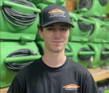 SERVPRO employee in black polo against a green background